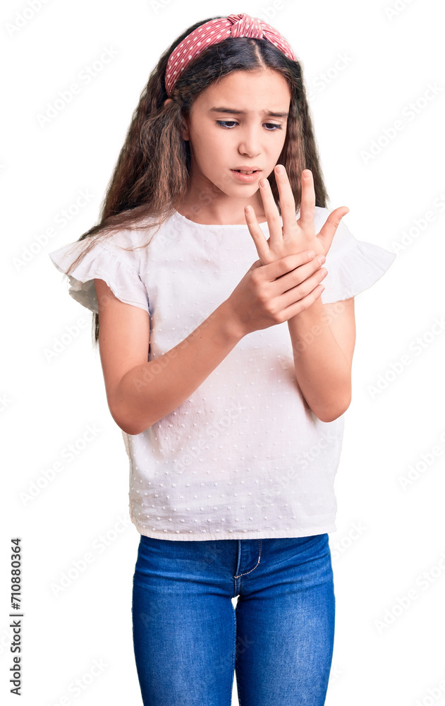 Cute hispanic child girl wearing casual white tshirt suffering pain on hands and fingers, arthritis inflammation Cute hispanic child girl wearing casual white tshirt suffering pain on hands and fingers, arthritis inflammation
