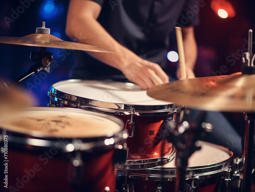 closeup photo of male hands of a person playing the drums with sticks. bokeh lights in the background. playing music instrument in the band studio. 