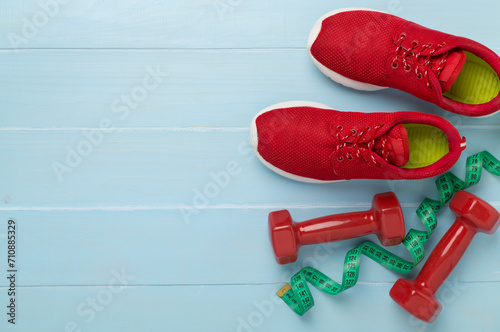 Sport equipment with tape measure on wooden background, top, view. Weight loss concept