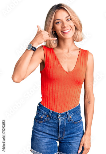 Beautiful caucasian woman wearing casual clothes smiling doing phone gesture with hand and fingers like talking on the telephone. communicating concepts.