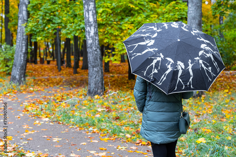 a woman with an umbrella in her hand walks through the autumn park.