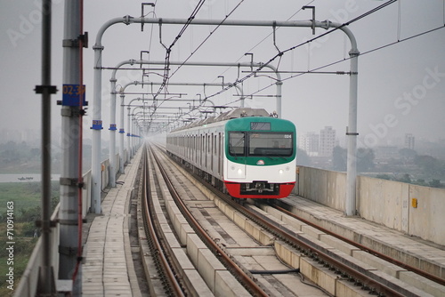 Dynamic shot of the Dhaka Metro Rail gracefully gliding along the tracks, symbolizing progress, modernity, and efficient urban transportation in the vibrant cityscape of Dhaka, Bangladesh. photo