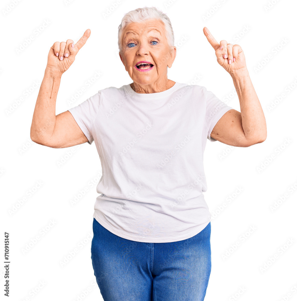 Senior beautiful woman with blue eyes and grey hair wearing casual white tshirt smiling amazed and surprised and pointing up with fingers and raised arms. Senior beautiful woman with blue eyes and grey hair wearing casual white tshirt smiling amazed and surprised and pointing up with fingers and raised arms.