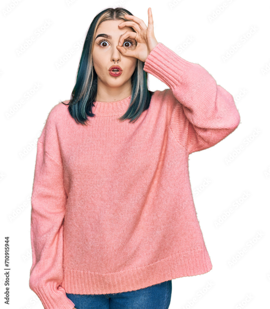 Young modern girl wearing pink wool winter sweater doing ok gesture shocked with surprised face, eye looking through fingers. unbelieving expression. Young modern girl wearing pink wool winter sweater doing ok gesture shocked with surprised face, eye looking through fingers. unbelieving expression.