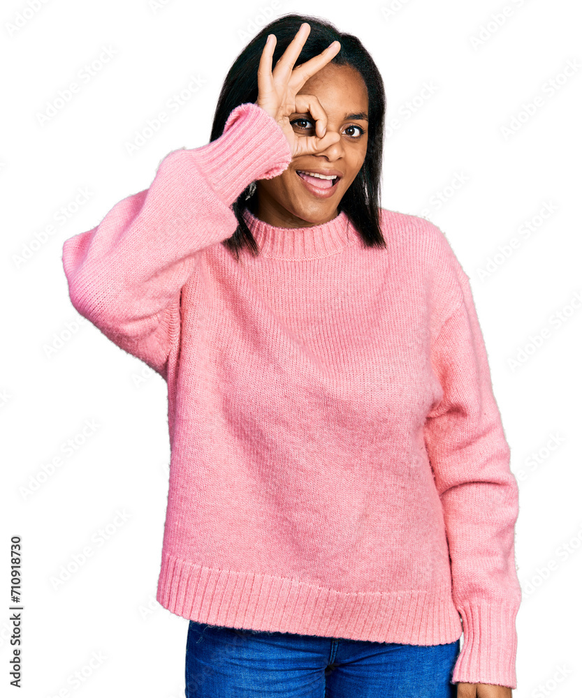 Beautiful hispanic woman wearing casual winter sweater doing ok gesture with hand smiling, eye looking through fingers with happy face. Beautiful hispanic woman wearing casual winter sweater doing ok gesture with hand smiling, eye looking through fingers with happy face.