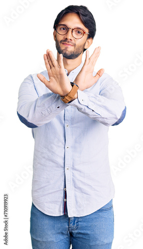 Handsome hispanic man wearing business shirt and glasses rejection expression crossing arms doing negative sign, angry face