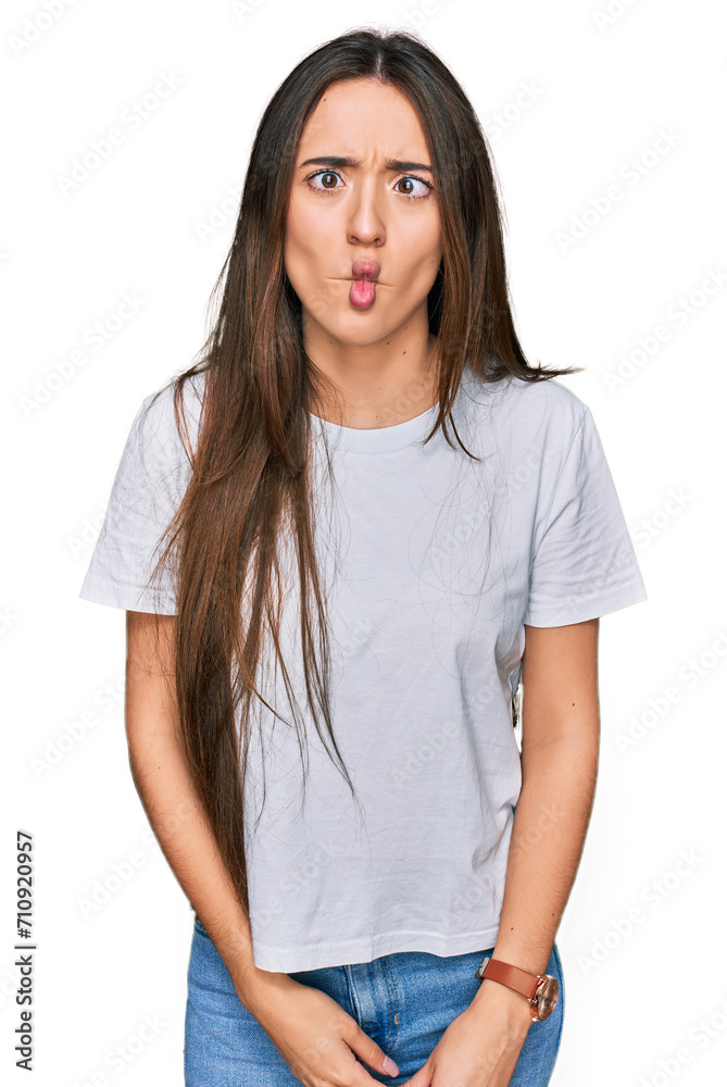 Young hispanic girl wearing casual white t shirt making fish face with lips, crazy and comical gesture. funny expression. Young hispanic girl wearing casual white t shirt making fish face with lips, crazy and comical gesture. funny expression.