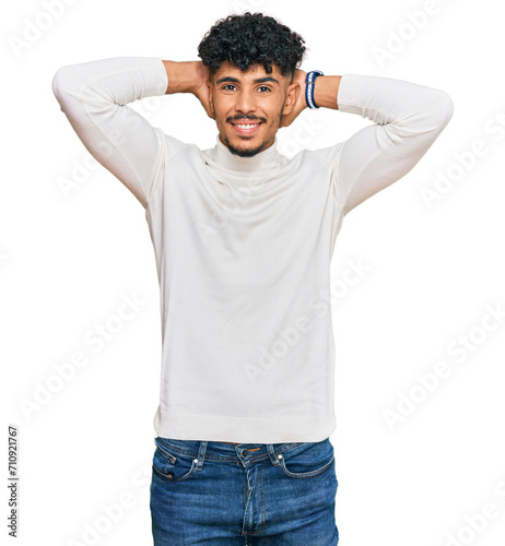 Young arab man wearing casual winter sweater relaxing and stretching, arms and hands behind head and neck smiling happy