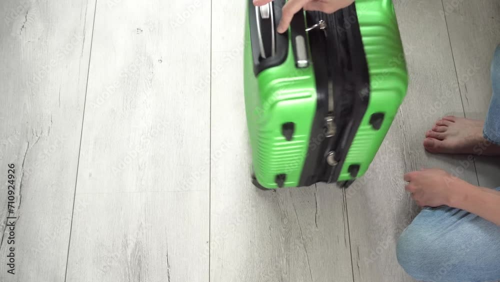 Guy rotate the green baggage case with clothes in hand Guy rotate the green baggage case with clothes in hand