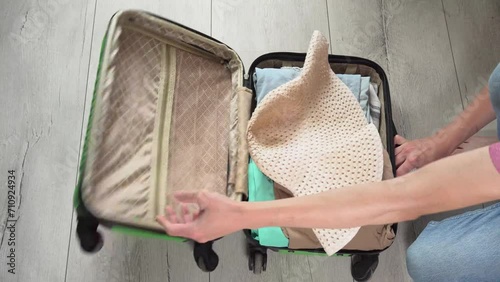 Guy opens the green baggage case and puts clothes in photo