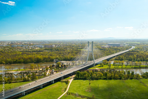 Cars drive on cable-stayed bridge under clear blue sky. Massive Redzinski Bridge over Oder river in sunny spring leading to Wroclaw aerial view photo