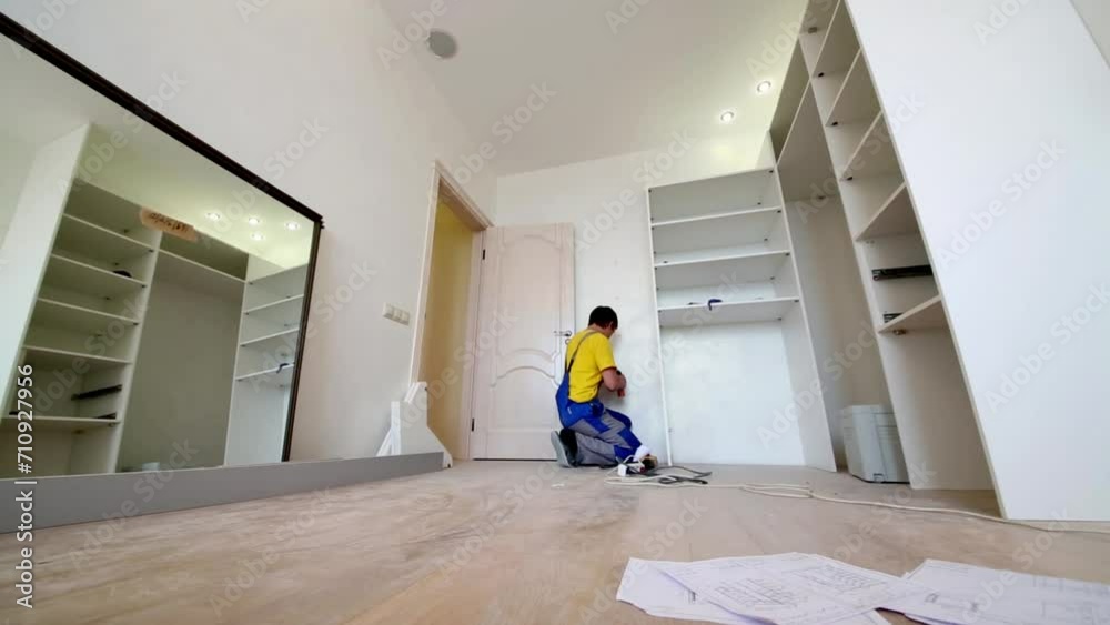 Man drills holes in the wall for mounting slide door wardrobe. Man drills holes in the wall for mounting slide door wardrobe.