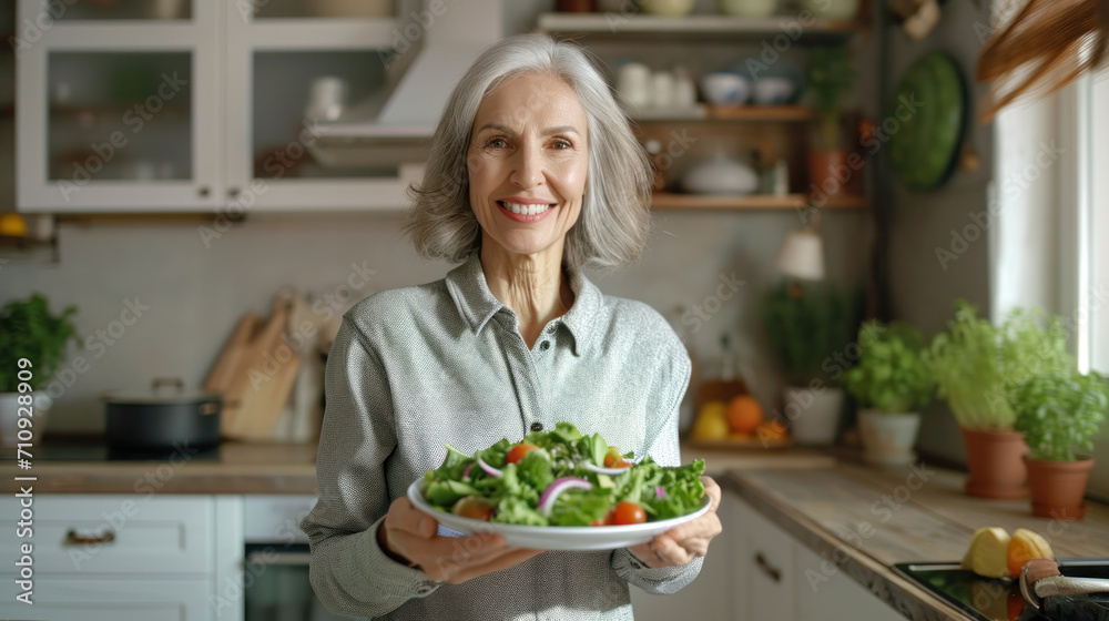 Elegant senior woman presenting a fresh garden salad in her kitchen