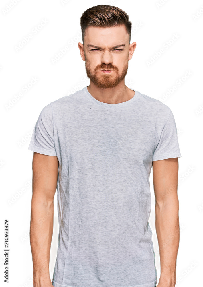 Fototapeta premium Young redhead man wearing casual grey t shirt puffing cheeks with funny face. mouth inflated with air, crazy expression.