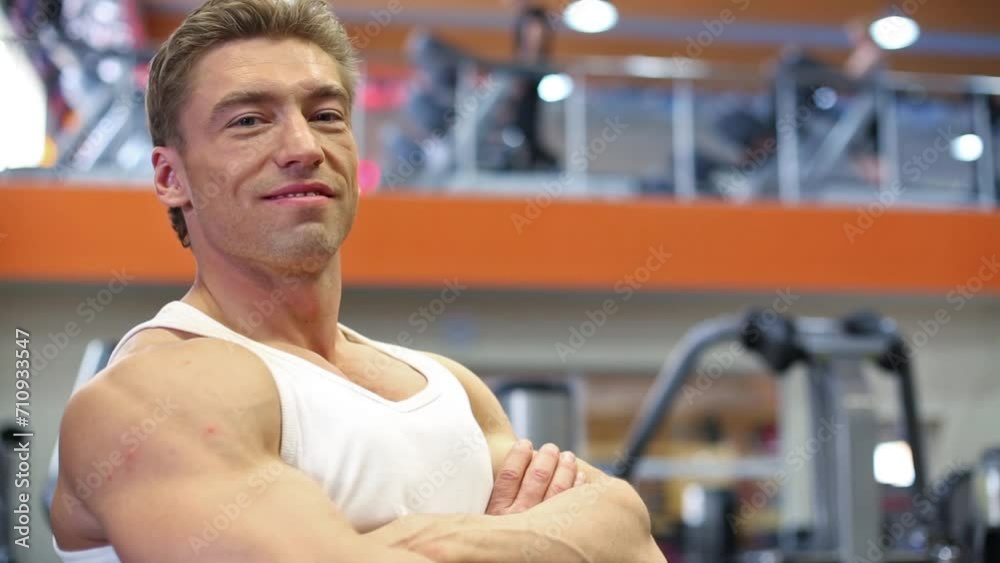bodybuilder stands with his arms crossed on chest in gym hall. bodybuilder stands with his arms crossed on chest in gym hall.