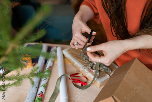 young woman hands wrapping christmas gifts, cropped faceless photo