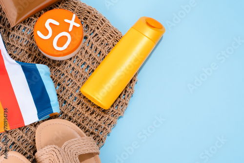 Summer composition sun protection product in yellow bottle with accessories on a blue background. 50 level sun protection for skin concept. Space for text. top view. photo