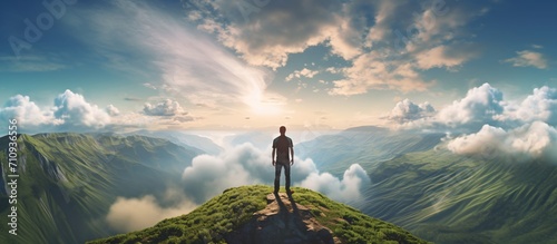 Man standing on top of a mountain looking at the clouds below