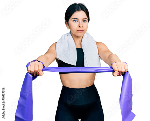 Young brunette woman with blue eyes training arm resistance with elastic arm bands relaxed with serious expression on face. simple and natural looking at the camera. © Krakenimages.com