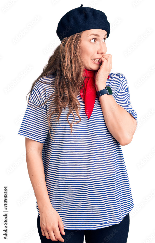 Young beautiful blonde woman wearing french beret and striped t-shirt looking stressed and nervous with hands on mouth biting nails. anxiety problem.