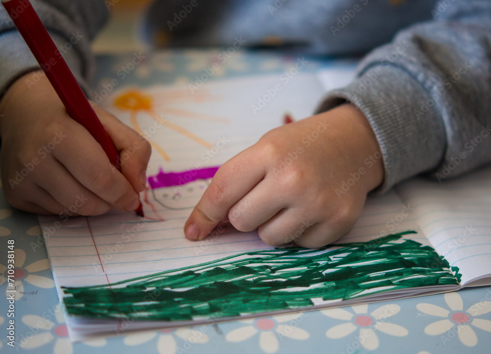 Obraz premium Children's hands draw with a felt-tip pen. girl sits at the table and draws