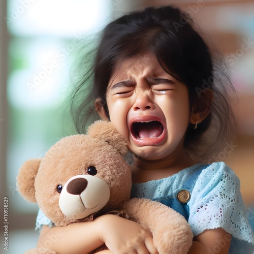 Menina chorando segurando ursinho fofinho de pelúcia photo