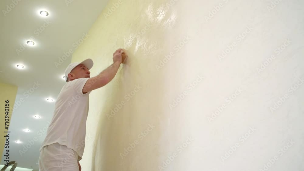Builder is polishing wall using the sanding sponge.