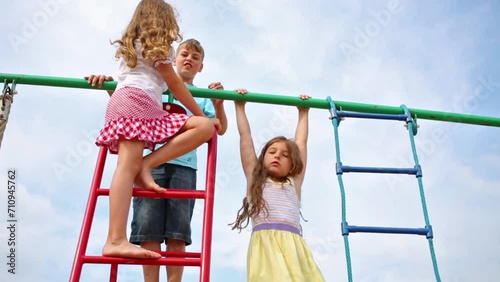 Three cheerful children at the top of playground equipment. photo