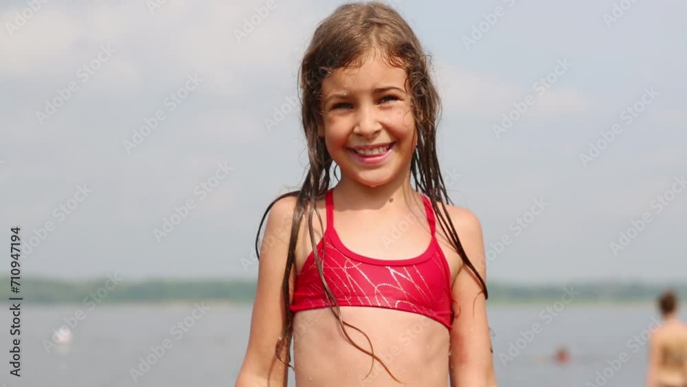 Cute smiling girl in a red swimsuit against the river. Cute smiling girl in a red swimsuit against the river.