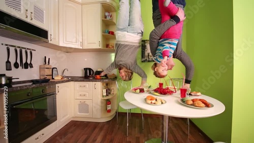 Parents and daughter upside down touch food in inverted house