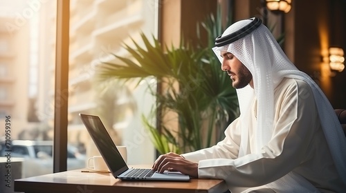 Arab man using laptop in cafe photo