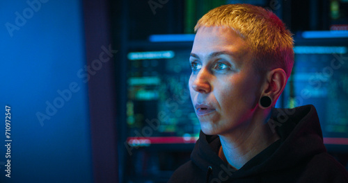 Close up of Caucasian woman cyber police worker sitting in front of computer screen at night and working. Female hacker thinking hard while creating virus or antivirus. Difficult IT work concept. photo