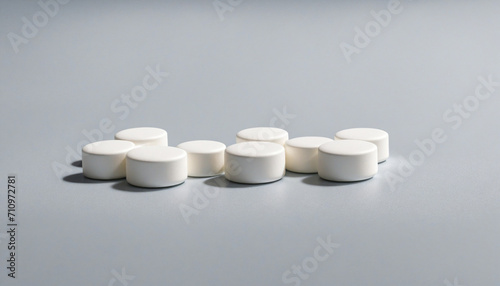 Close-up view of white antacid tablets on silver surface with shadows. Alleviates stomach pain caused by excess gastric acid. Symbol of pharmaceutical sector and worldwide healthcare.