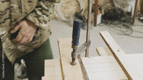 A carpenter secures a piece of wood using a screw clamp. Fastening the part. Close-up. photo