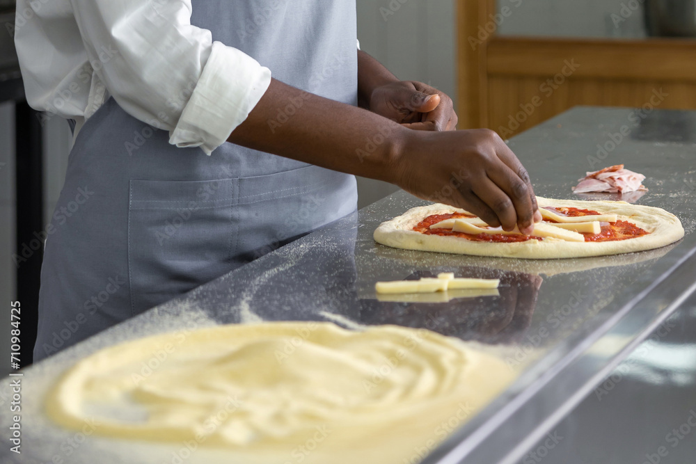 Dark-skinned woman preparing dough for pizza Dark-skinned woman preparing dough for pizza