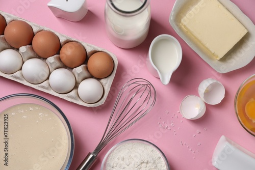 Flat lay composition with whisk and dough in bowl on pink background