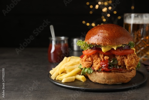 Delicious burger with crispy chicken patty and french fries on black table. Space for text