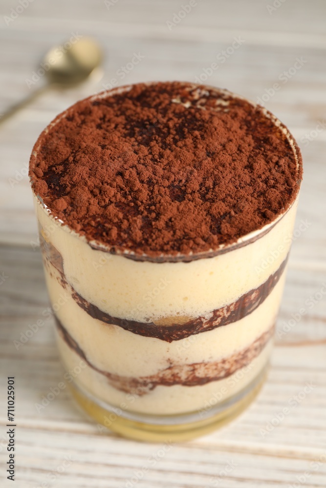 Delicious tiramisu in glass on light wooden table, closeup Delicious tiramisu in glass on light wooden table, closeup