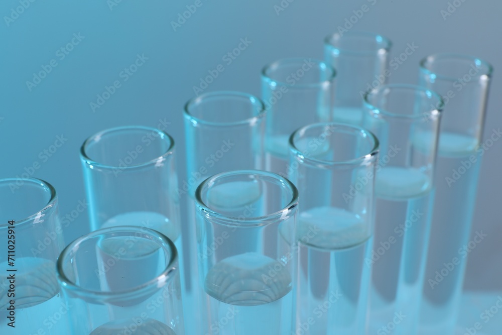 Laboratory analysis. Many glass test tubes on light blue background, closeup Laboratory analysis. Many glass test tubes on light blue background, closeup