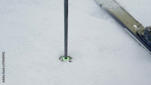 Close up sticking ski pole in the snow to begin skiing on snowy mountain. Stabbing the snow with sharp tip of pole to push skier before going downhill in cold winter conditions
