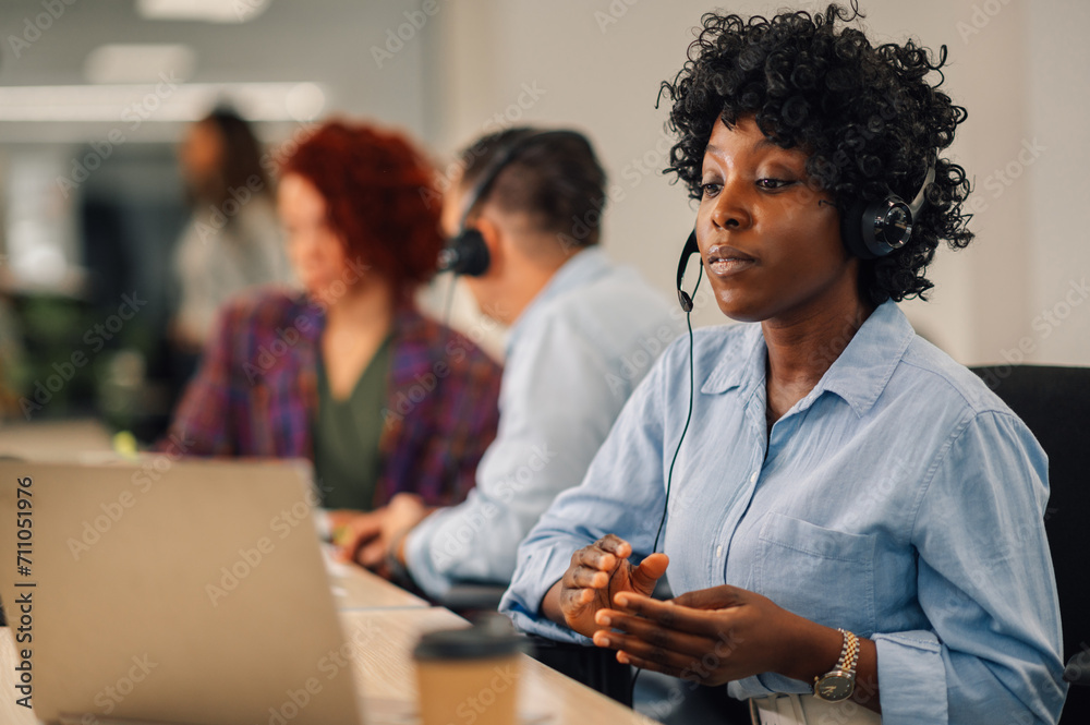 An interracial customer support agent is having phone call on headset. An interracial customer support agent is having phone call on headset.