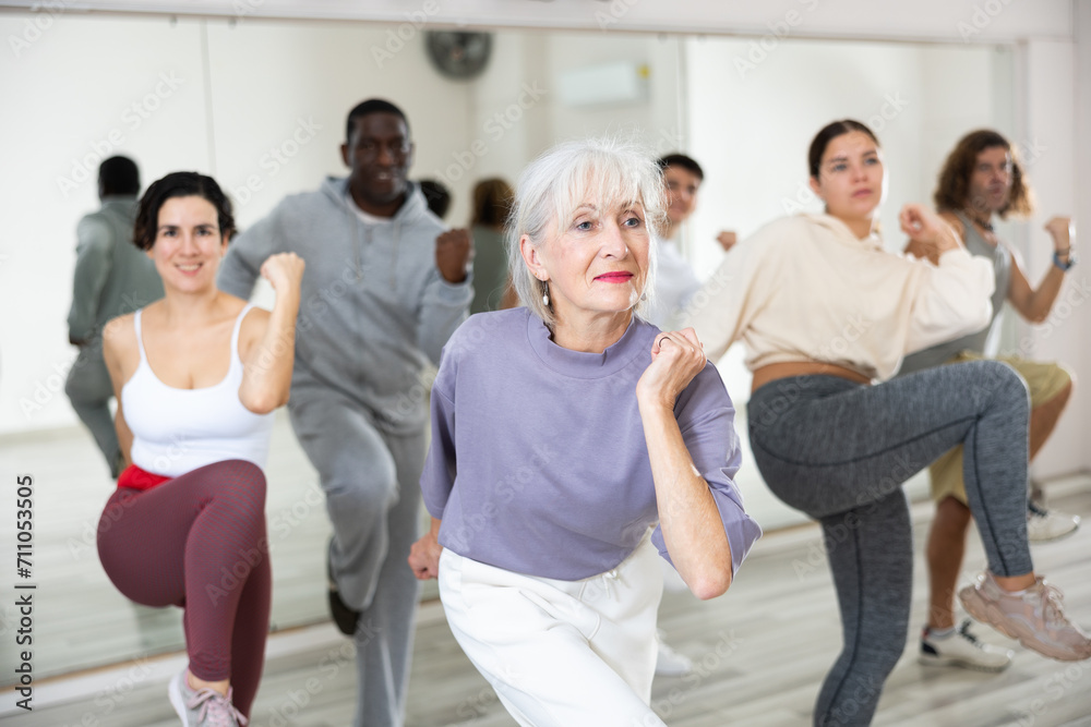 Fototapeta premium Energetic elderly lady attending group choreography class, learning modern dynamic dances. Concept of active lifestyle of older generation..