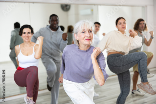 Energetic elderly lady attending group choreography class, learning modern dynamic dances. Concept of active lifestyle of older generation..