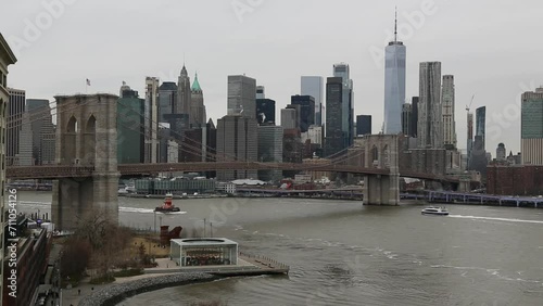 nyc skyline view with water moving on a gray overcast sky day (ferries on the water, view from manhattan bridge, dumbo carousel) downtown footage with one world trade center, brooklyn bridge  photo