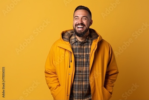 Portrait of a laughing bearded man in yellow jacket on yellow background