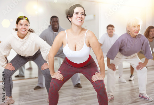 Cheerful sporty young Hispanic woman having fun and dancing hip hop during workout in group dance class for adults