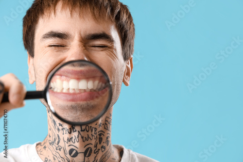 Young tattooed man magnifyi...