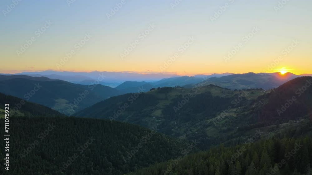 Beautiful nature landscape. Aerial view of colorful sunset in wild mountains. Dark pine forest illuminated with bright setting sun Beautiful nature landscape. Aerial view of colorful sunset in wild mountains. Dark pine forest illuminated with bright setting sun