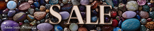 A stunning collection of diverse gemstones and crystals, surrounding the metallic, three-dimensional text "SALE", creating a vibrant and attractive advertisement.