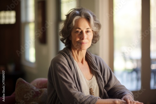 A Tranquil Moment Captured: Mature Woman with Soft Blue Eyes Reflects on Life's Journey, Seated Comfortably in Her Favorite Cardigan in a Sunlit Room